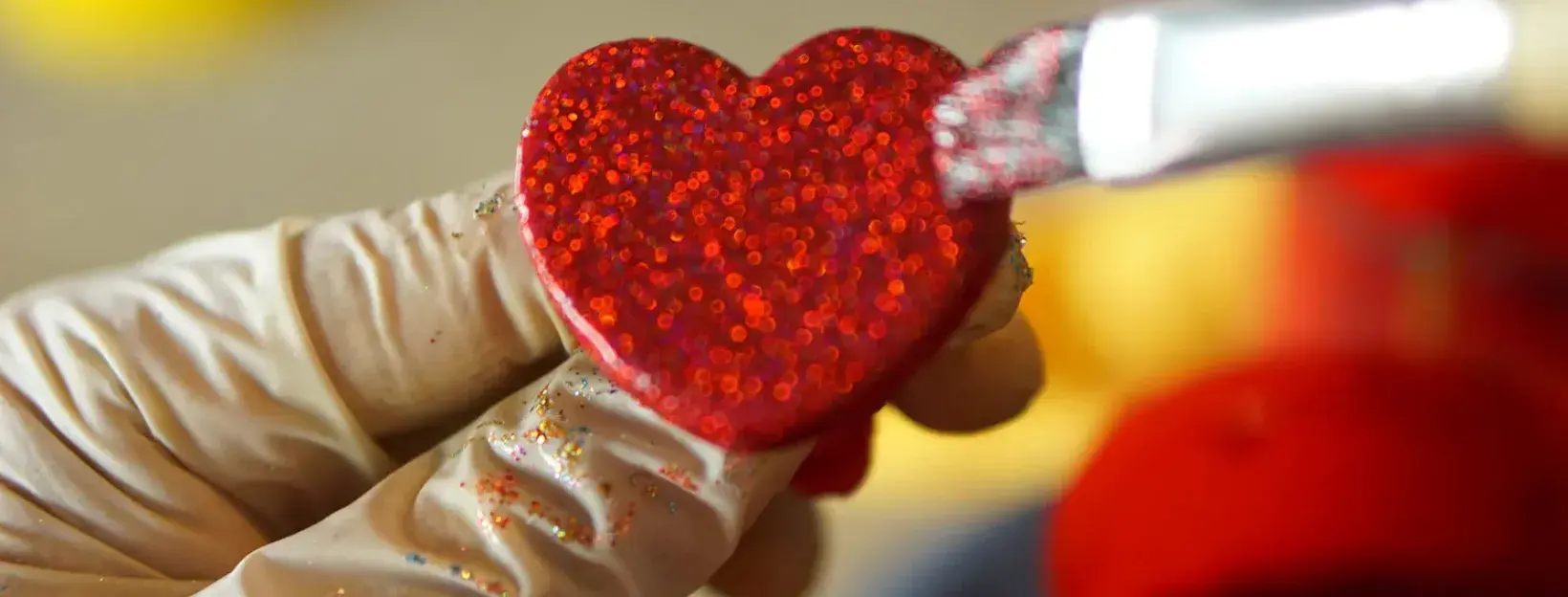 A sparkling red heart detail being carefully painted by hand.